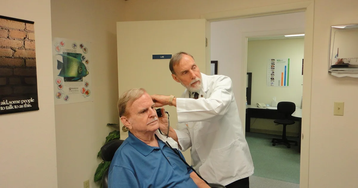 Audiologist fitting a patient with hearing aids